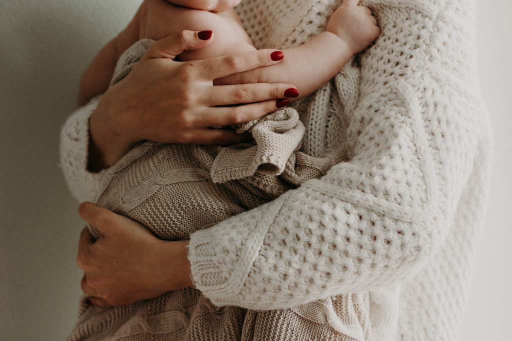 Mama-Baby-Yoga. Mutter hält Baby auf dem Arm